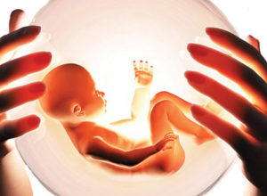 Женские руки держат сферу с младенцем