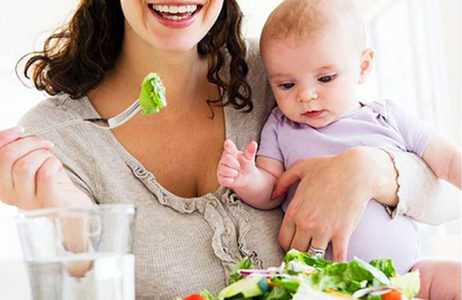 Мамочка с малышом на руках ест салат