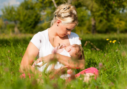 Молодая мамочка кормит ребенка на природе