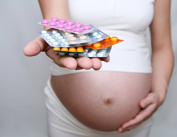 Беременная держит горсть лекарств