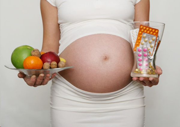 Беременная с фруктами и таблетками в руках